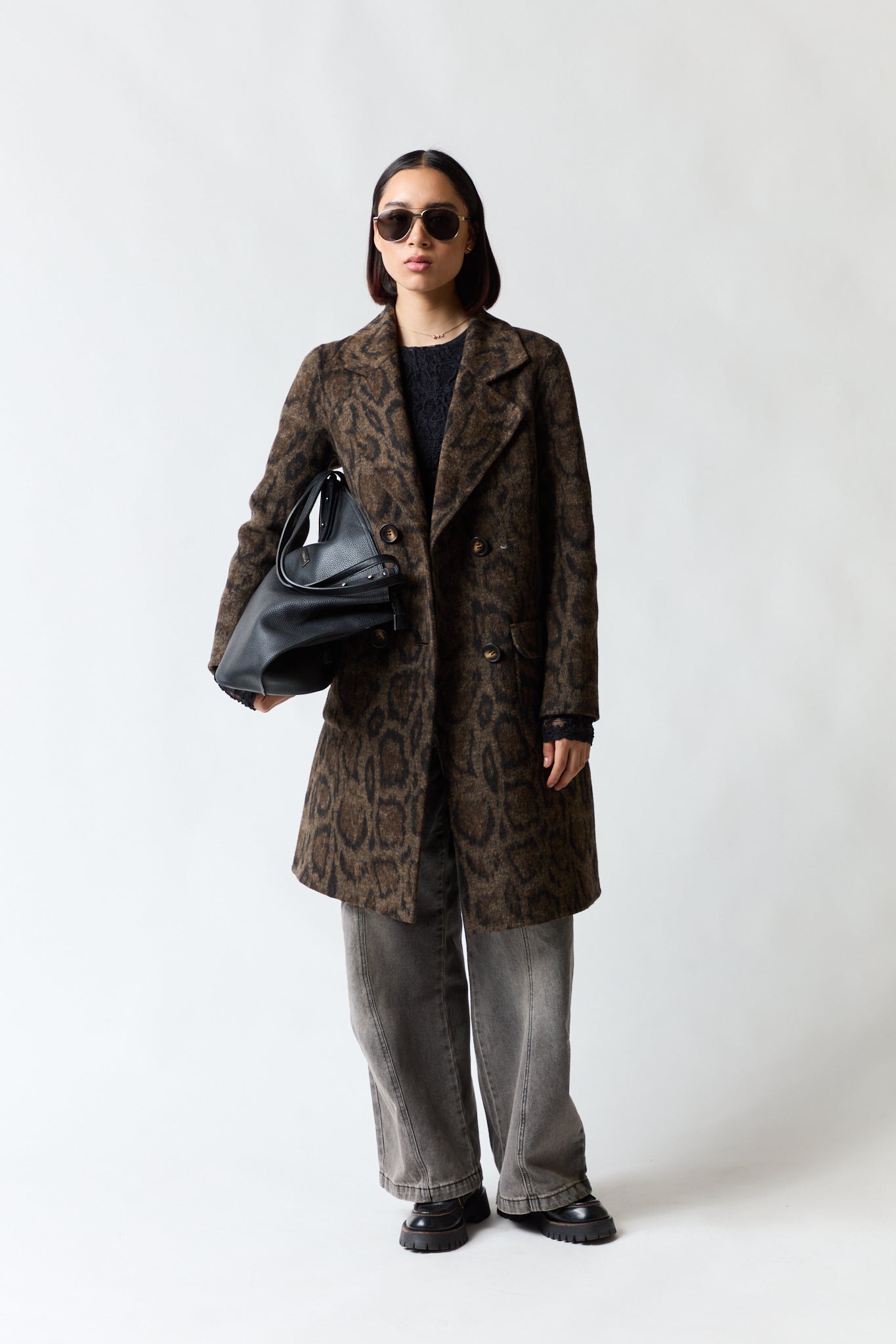 mujer vistiendo chaqueta café Umbrale, estilo urbano en estudio