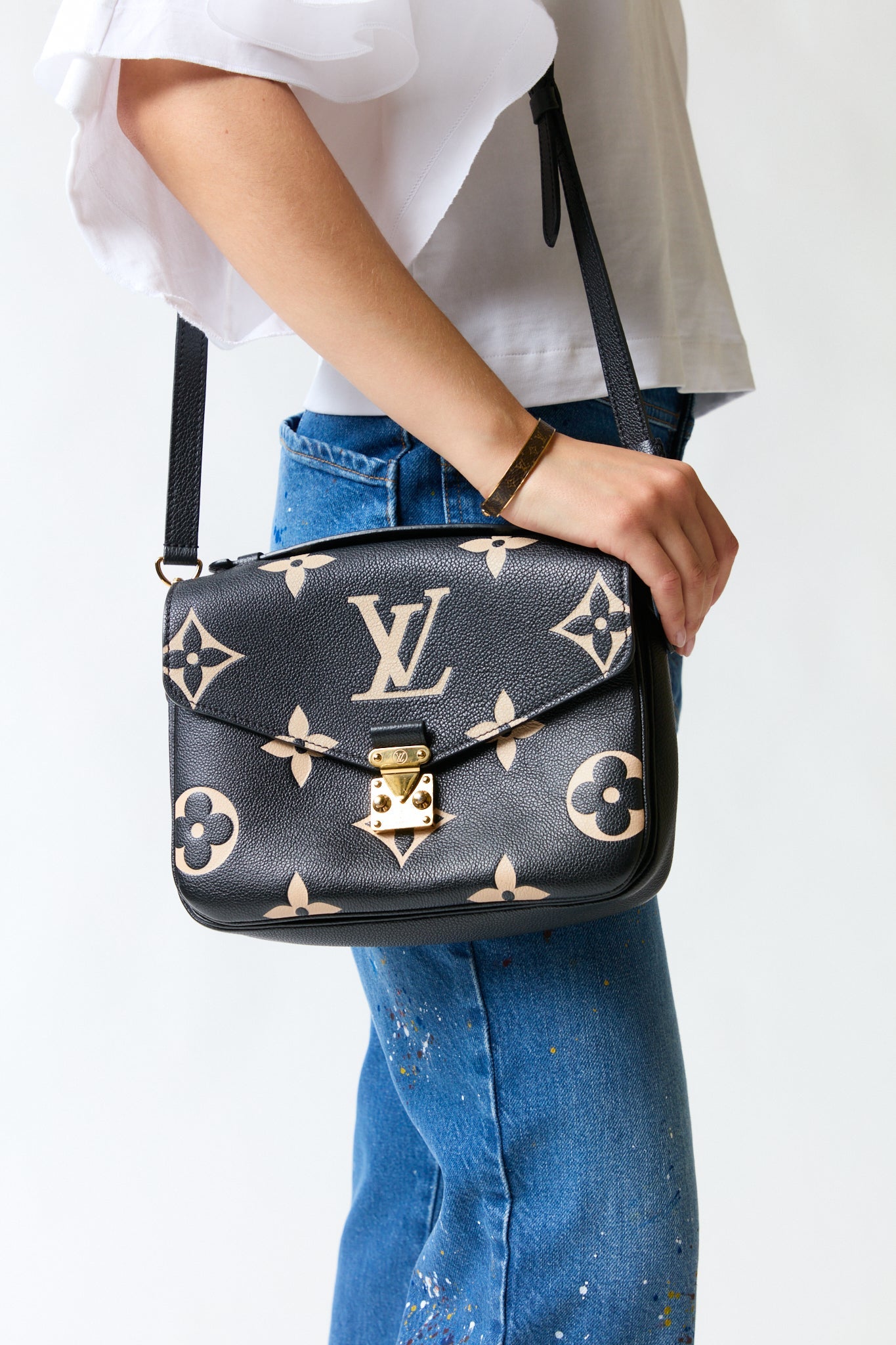 mujer vistiendo producto negro dorado LV, estilo urbano en estudio