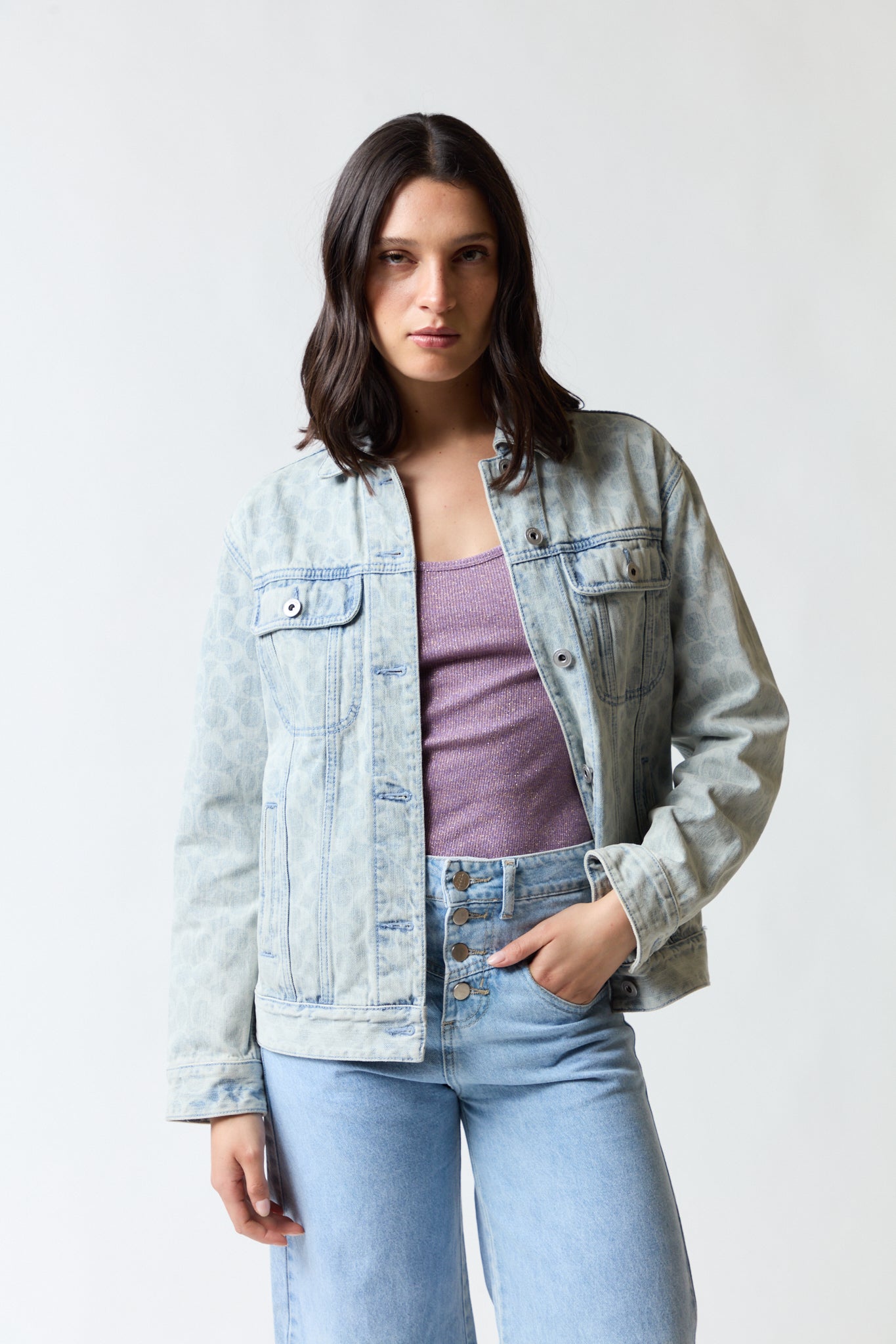 mujer vistiendo chaqueta denim azul Coach, estilo urbano en estudio