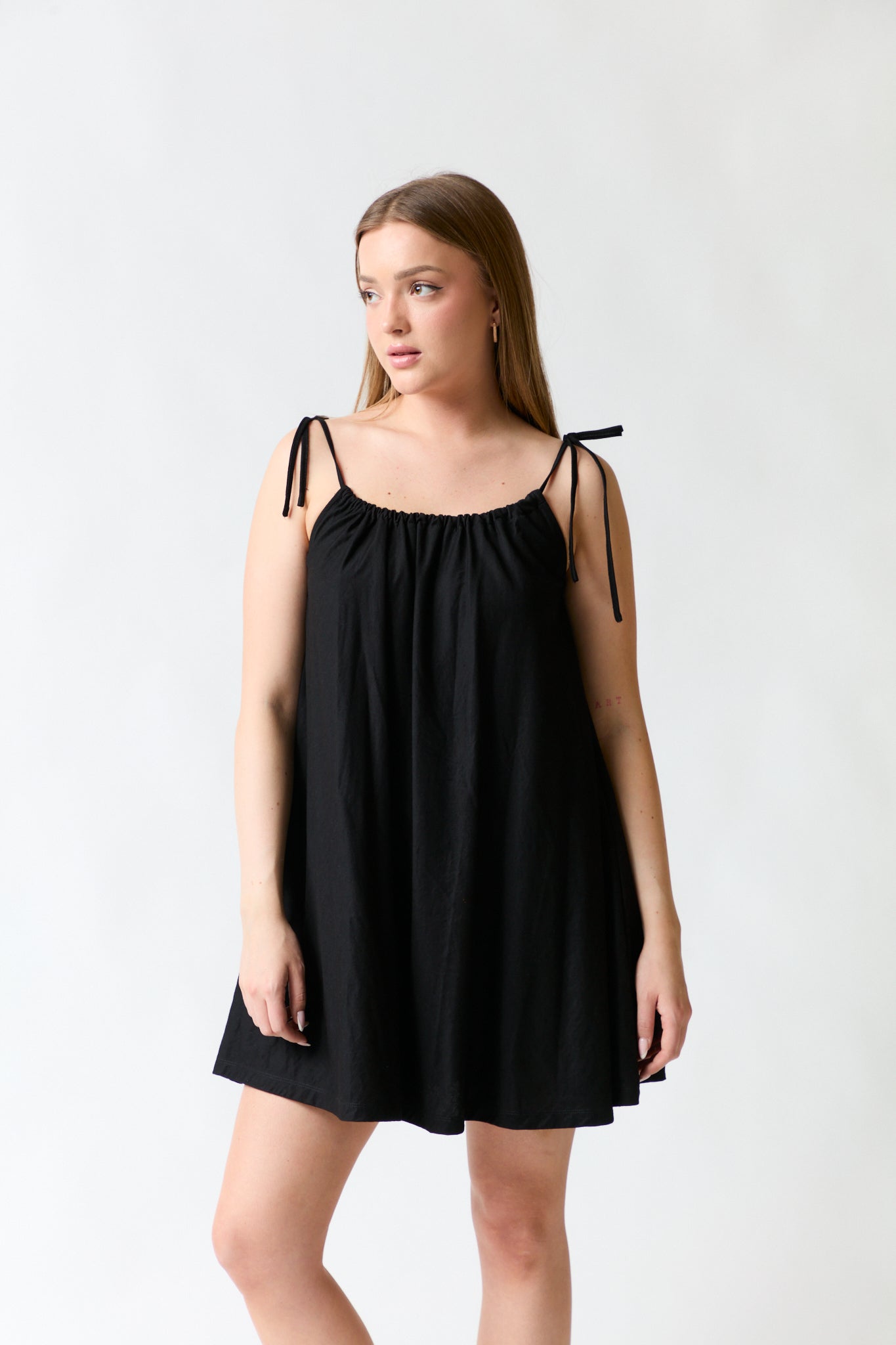 mujer vistiendo vestido negro Mango, estilo urbano en estudio