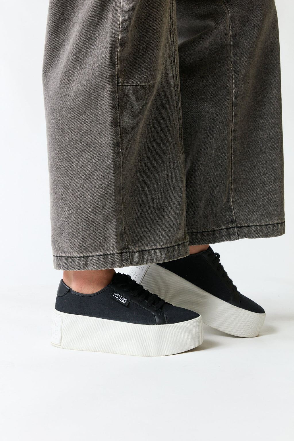 mujer vistiendo producto negro Versace, estilo urbano en estudio